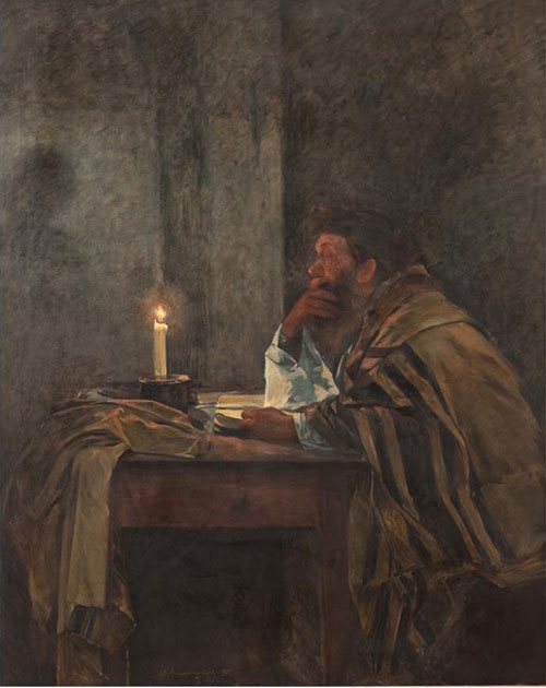   An elderly bearded man sits at a table, wearing a Jewish prayer shawl (Talith). The room is dark and a single burning candle i