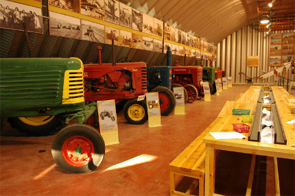   A large warehouse with tractors of various kinds. Historic photos adorn the walls.